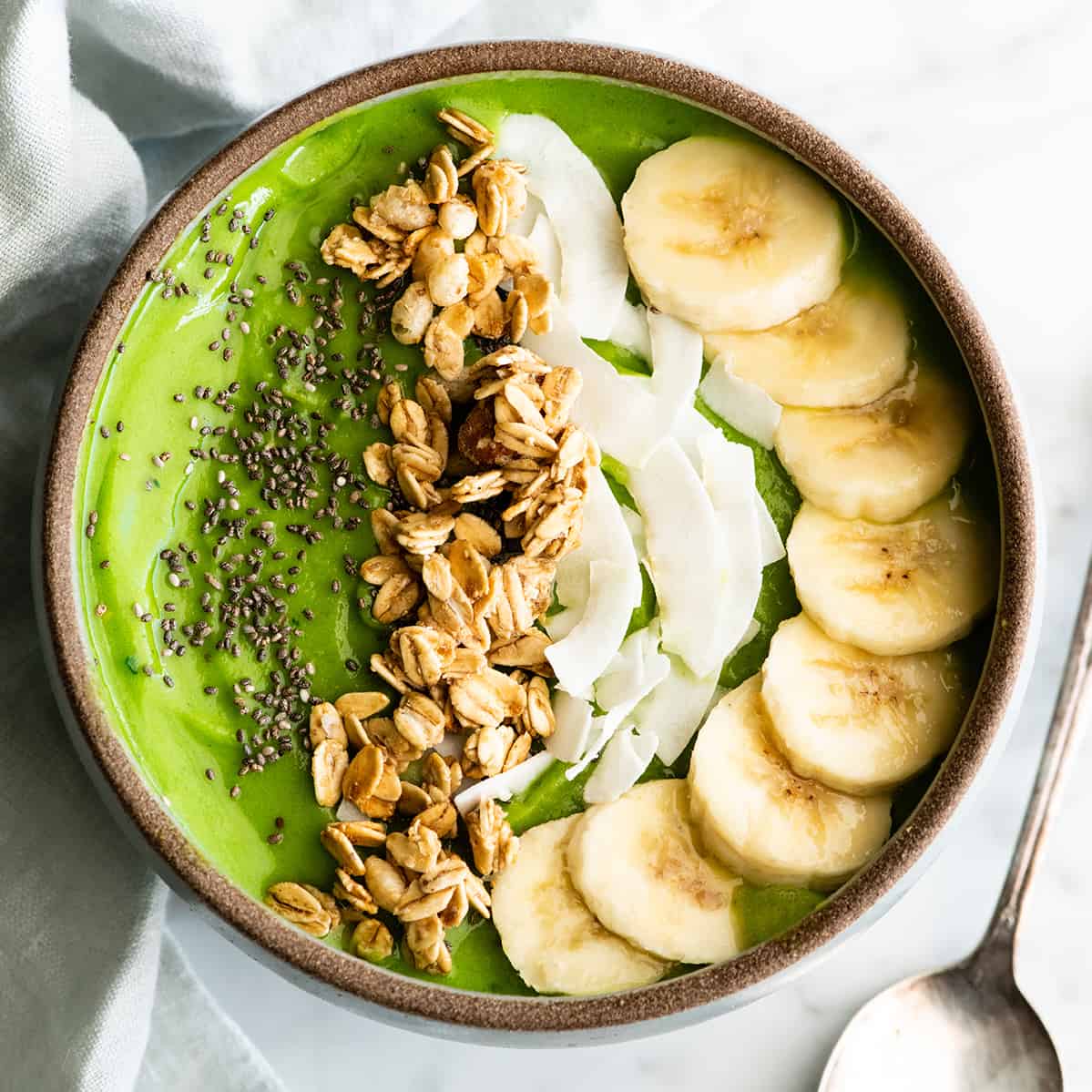 Follow our step-by-step photos & video to learn how to make the BEST easy & healthy smoothie bowl recipe (3 varieties) with 5 ingredients in 5 minutes! Smoothie bowls make the best breakfast, brunch or snack, and you can save so much money making them at home! Paleo, dairy-free and vegan-friendly. overhead view of a green smoothie bowl