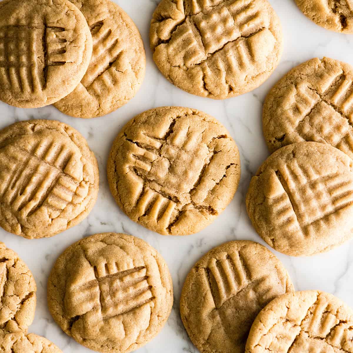 This is the BEST peanut butter cookie recipe ever! These classic, soft peanut butter cookies are easy to make, loaded with peanut butter, and will definitely become your new favorite peanut butter cookie recipe! Learn how to make peanut butter cookies by following our step-by-step instructions and watching the video! #peanutbuttercookies #cookies #peanutbutter #dessert overhead view of 12 peanut butter cookies