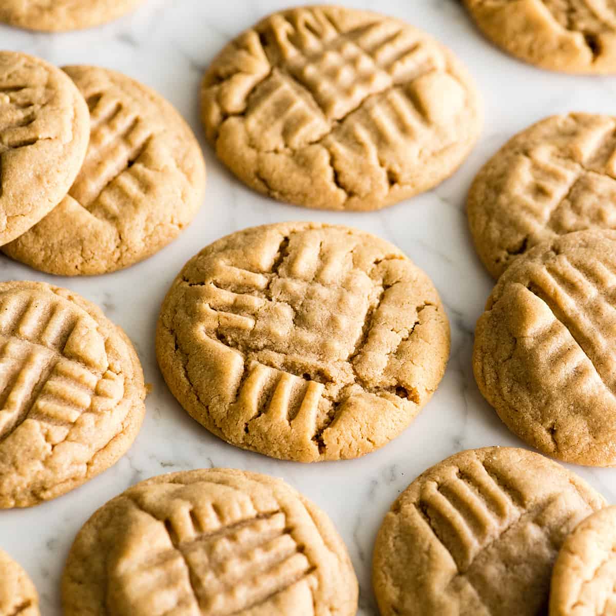 This is the BEST peanut butter cookie recipe ever! These classic, soft peanut butter cookies are easy to make, loaded with peanut butter, and will definitely become your new favorite peanut butter cookie recipe! Learn how to make peanut butter cookies by following our step-by-step instructions and watching the video! #peanutbuttercookies #cookies #peanutbutter #dessert front view of 12 peanut butter cookies