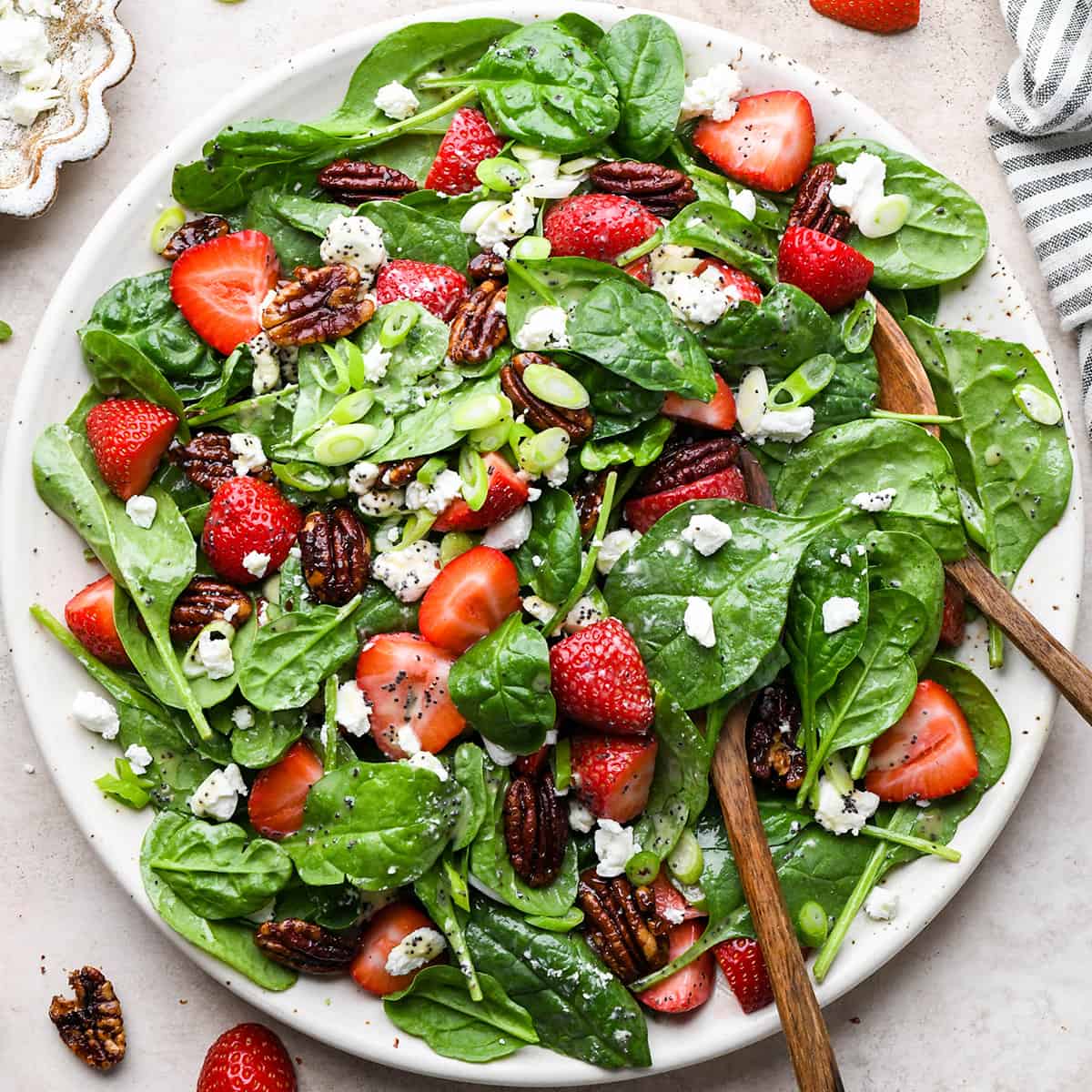 Strawberry Spinach Salad on a serving plate with a serving spoon