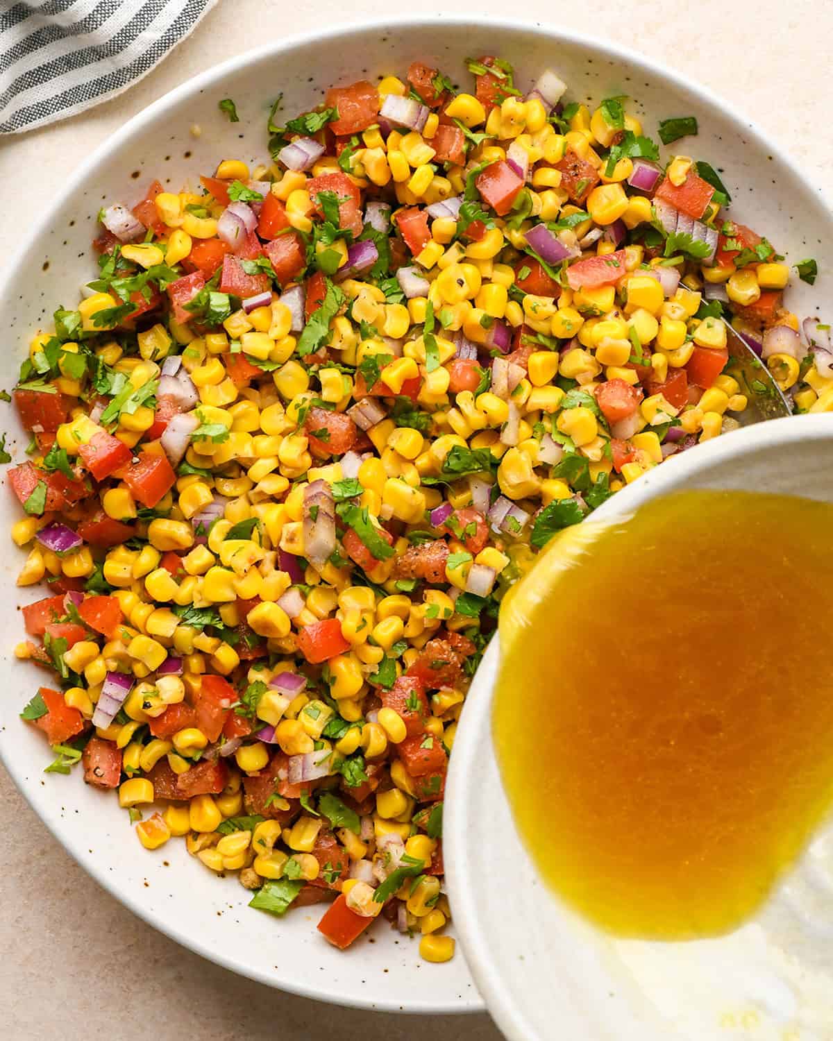 How to Make Corn Salsa - dressing being poured over the salsa ingredients in a bowl