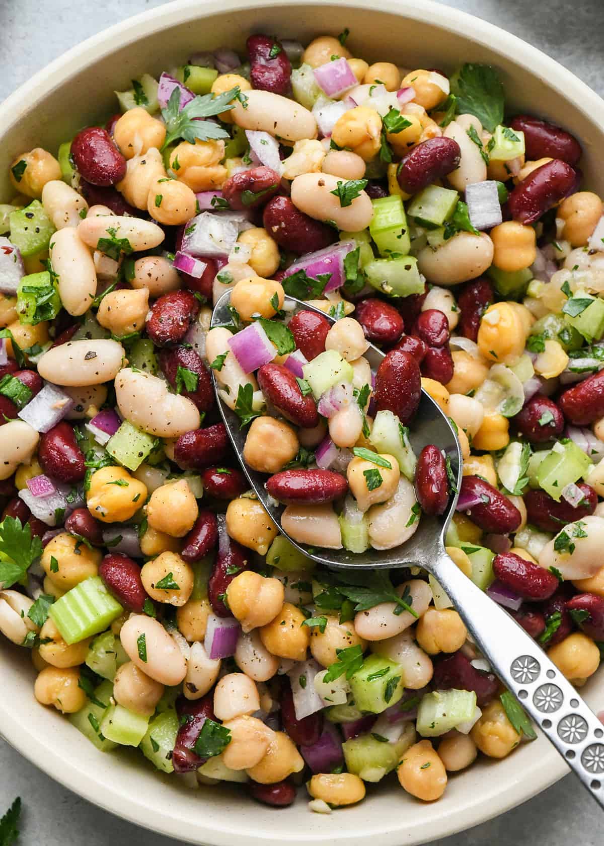 up close photo of three bean salad in a bowl with a spoon