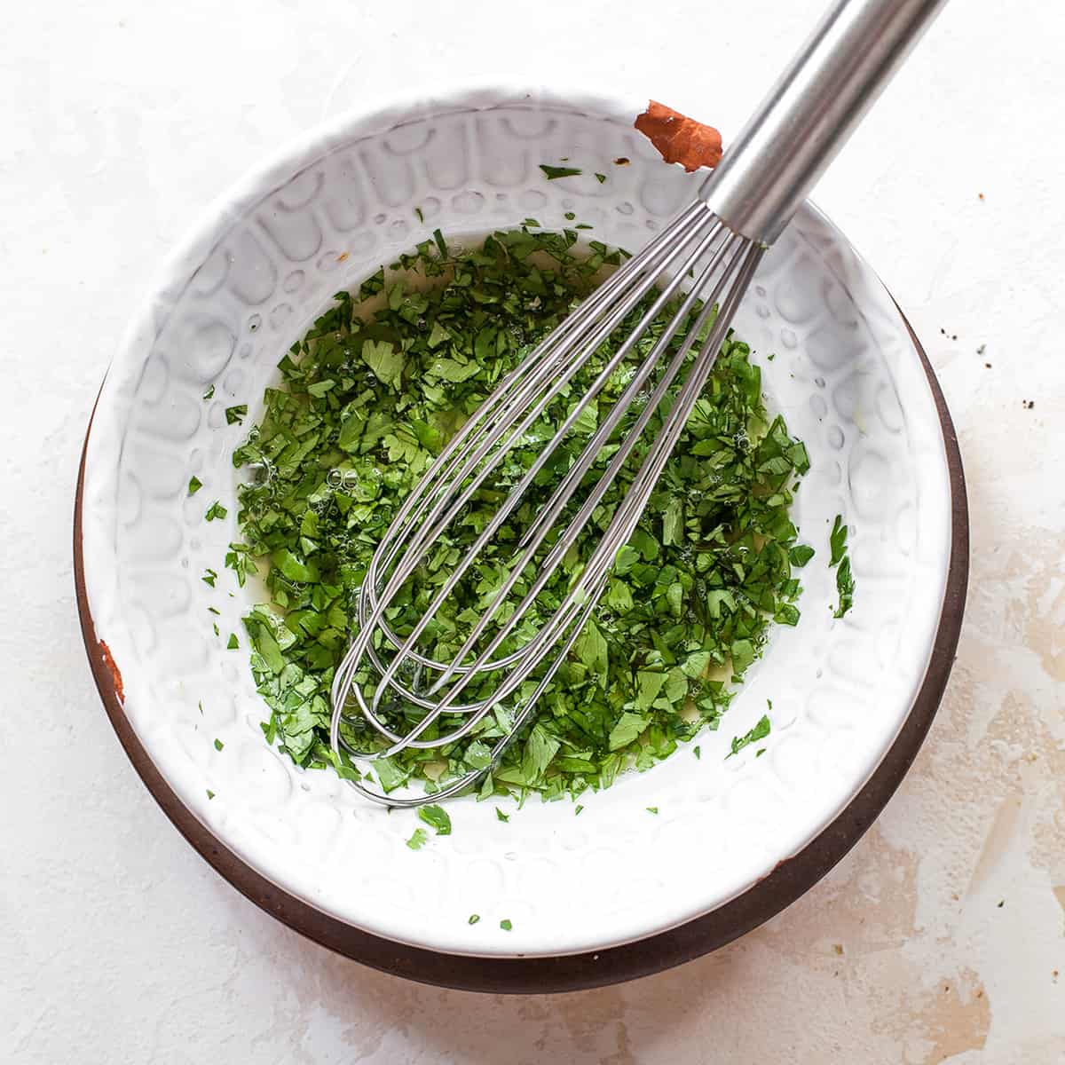 whisking together the sauce for sweet potato tacos in a white bowl