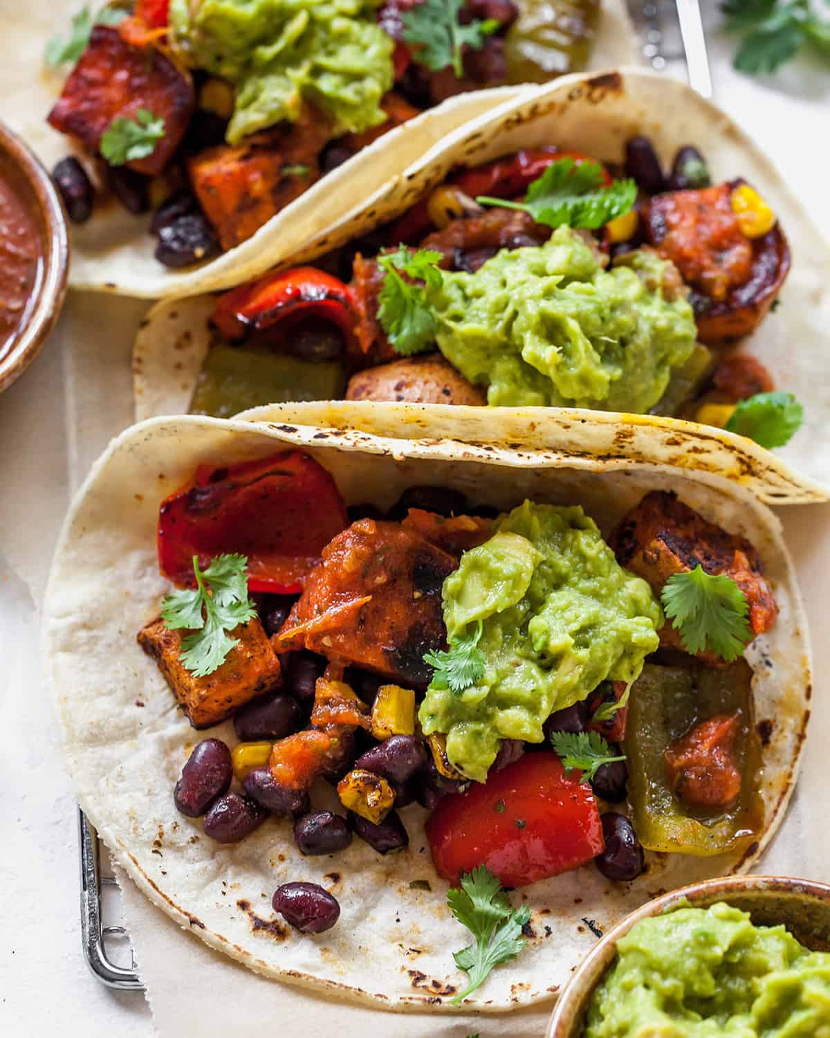 overhead view of three black bean sweet potato tacos with guacamole