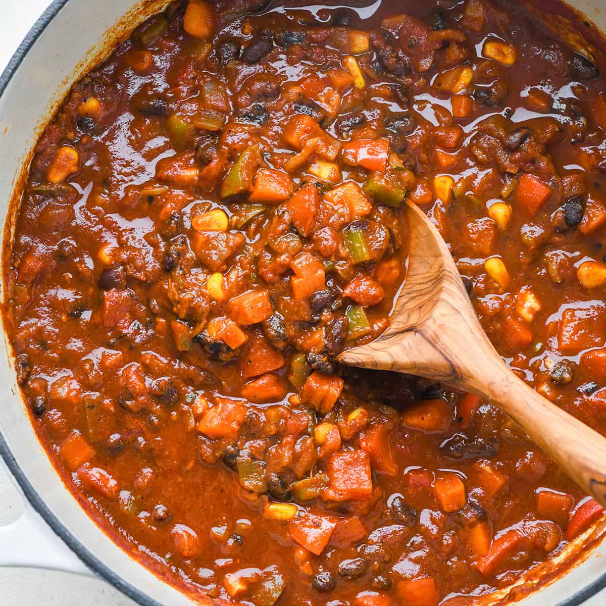 Vegetarian Chili in a pot with a wooden spoon taking a scoop