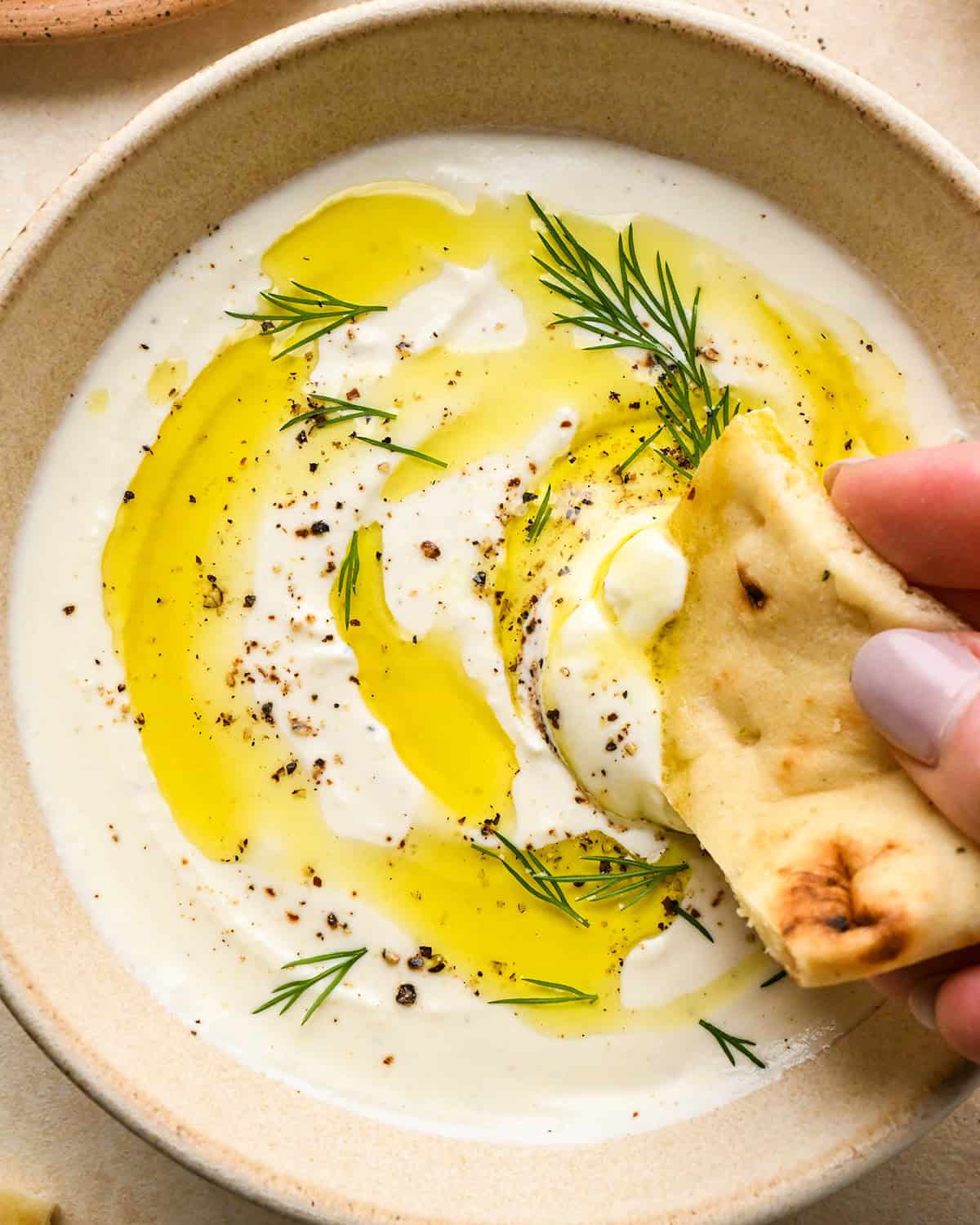 a piece of bread being dipped into Whipped Feta Cheese Dip