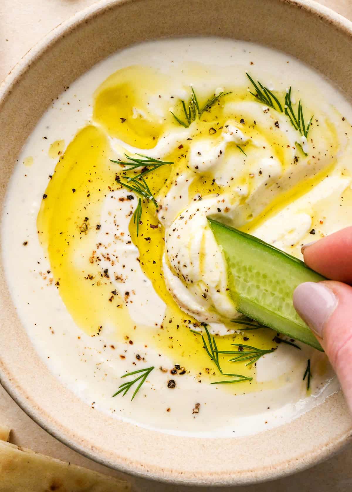 a cucumber being dipped into a bowl of Whipped Feta Cheese Dip
