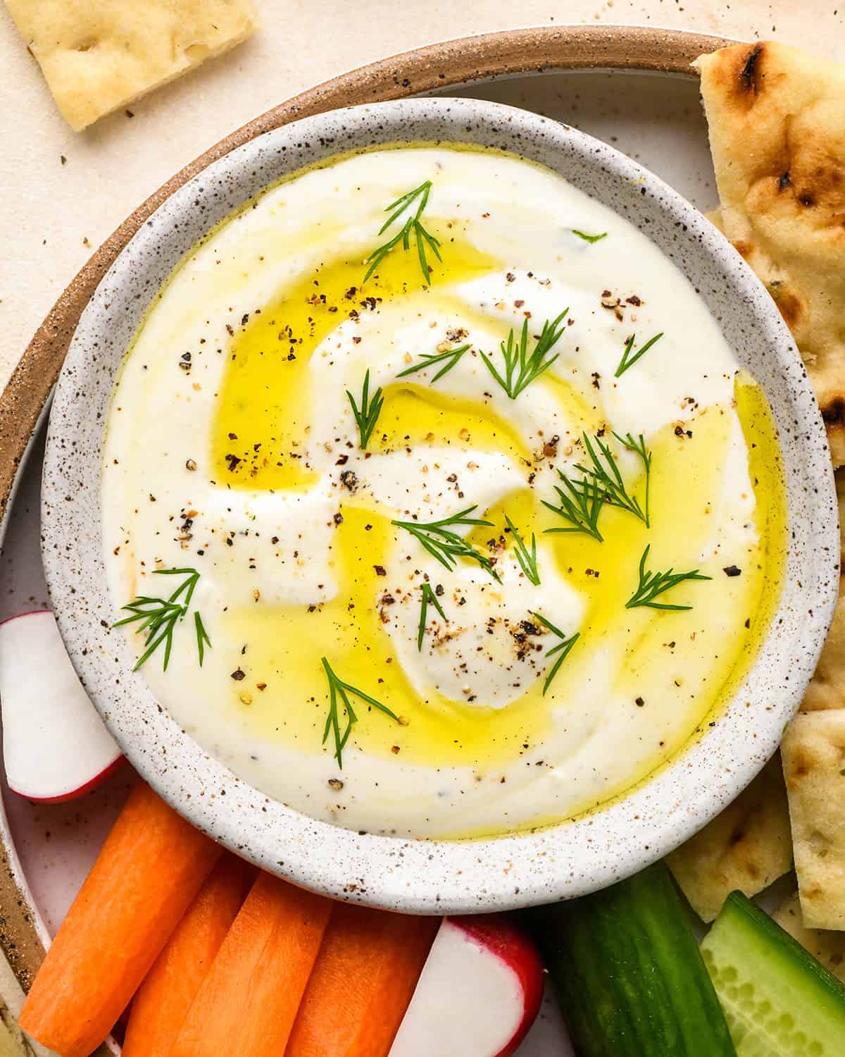 Whipped Feta Cheese Dip in a bowl garnished with pepper, dill and olive oil