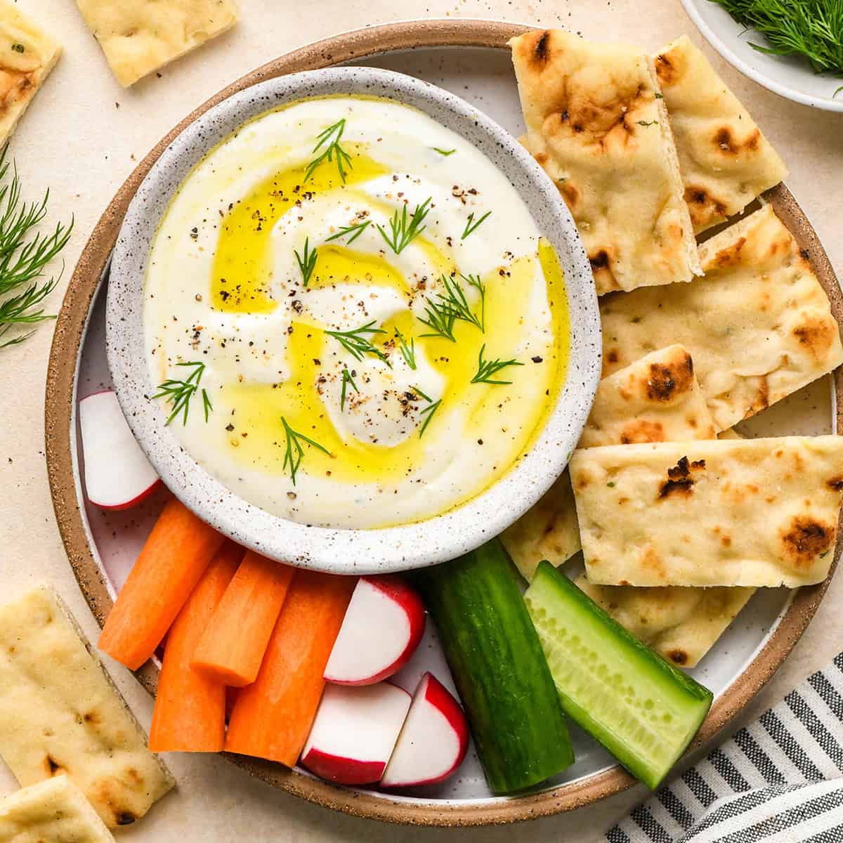 Whipped Feta Cheese Dip in a bowl on a plate with bread and vegetables