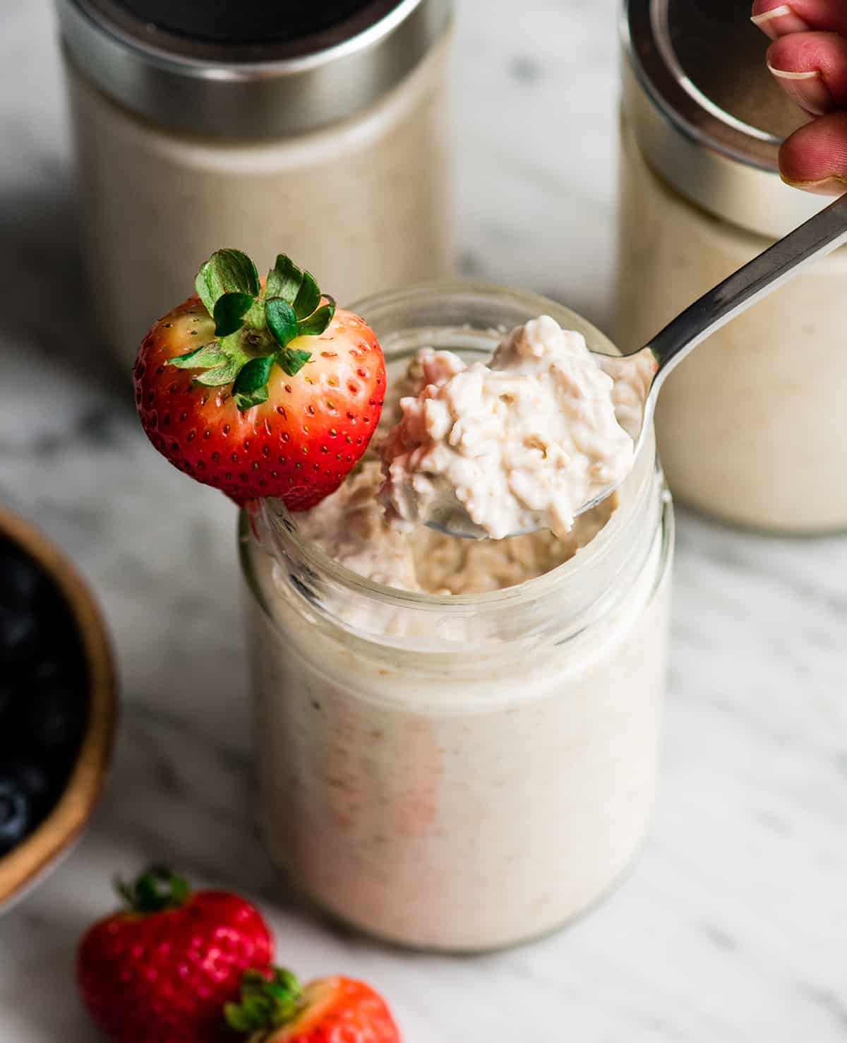 Easy Overnight Oats with Yogurt are a great healthy high-protein breakfast! This recipe only takes 6 ingredients and 5 minutes to prepare! Plus it's no-cook, gluten-free and can easily be made dairy-free! #overnightoats #oatmeal #greekyogurt #yogurt #glutenfree #breakfast #healthyrecipe #mealprep overhead photo of a spoon taking a bite of Yogurt Overnight Oats out of a glass jar